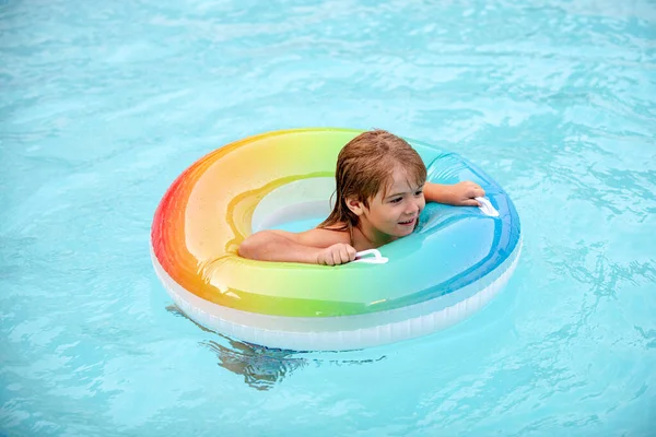 Kinderen zwemmen in de zomer. Zomervakantie. Kind in het aquapark. Grappige jongen op opblaasbare rubberen cirkel in zwembad. — Stockfoto