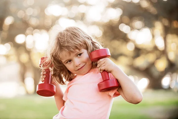 Attività sportiva. Allenamento per ragazzi con manubri nel parco. Ragazzo sportivo. Bambino che esercita all'aperto. — Foto Stock