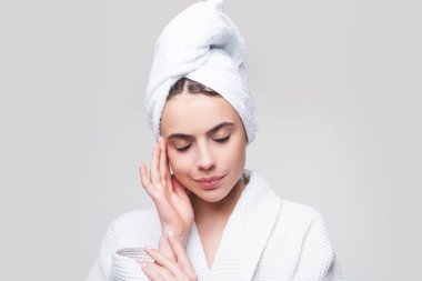 Şehvetli bir kız yüzüne nemlendirici krem sürüyor. Kusursuz ciltli genç bir kızın fotoğrafı. Cilt bakımı ve güzellik kavramı.