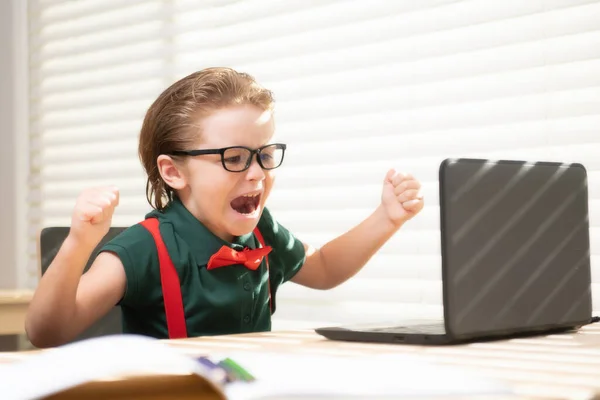 Slimme schooljongen thuis die huiswerk schrijft. Kleine student met notebook computer klaar om te studeren. School op afstand, online leren. Kind in de thuisklas leren. — Stockfoto