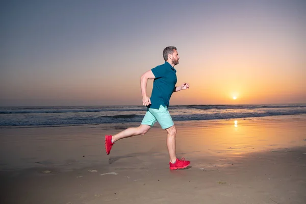 Sportlicher junger Mann läuft. Fit männlicher Fitnessläufer beim Outdoor-Training mit Sonnenuntergang im Hintergrund. — Stockfoto