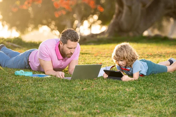 Outdoor learning. Blogging. Happy father using laptop relax with schooler son holding laptop. Childhood and parenthood kids concept. Video lesson.
