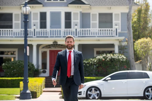 Homem de negócios a andar à porta de uma casa moderna. Conceito imobiliário. Agente pronto para vender para casa. — Fotografia de Stock