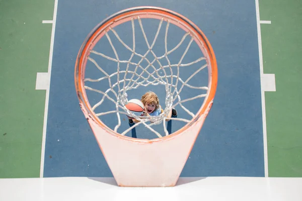 Dzieciak gra w koszykówkę. Wesoły chłopak koszykarz gospodarstwa piłkę gry. — Zdjęcie stockowe