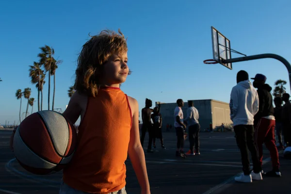 Sevimli çocuk basketbol oynuyor. Aktif çocuklar, Venice Beach basketbol sahasında basketbol topuyla dışarıda eğleniyorlar.. — Stok fotoğraf