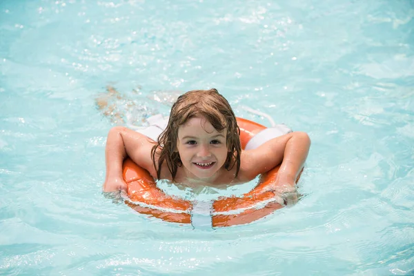 Child in summer pool. Kids summer holidays. Boy having fun at aquapark. Happy child playing with lifebuoy. Summer child.