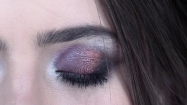 Yakın çekim göz makyajı. Göz farı takılıyor. Moda ve güzellik kozmetiği.