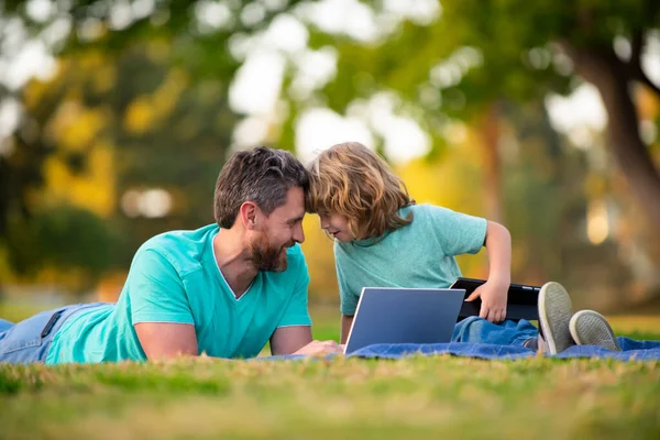 Gelukkige vader en zoon genieten van de zomertijd op vakantie in een zonnig park. Online les. — Stockfoto