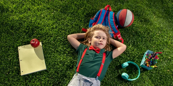 Kid studying online outdoor in park. Study in nature. Online school classes. Top view of little boy laying on green grass. — Stock Photo, Image