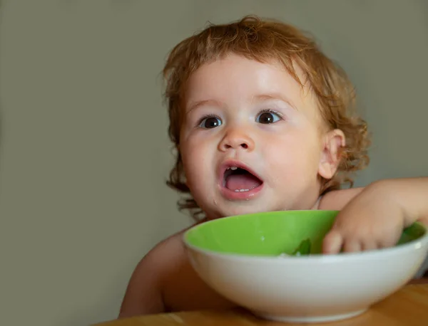 Kind baby eet soep in de keuken met gerechten. — Stockfoto