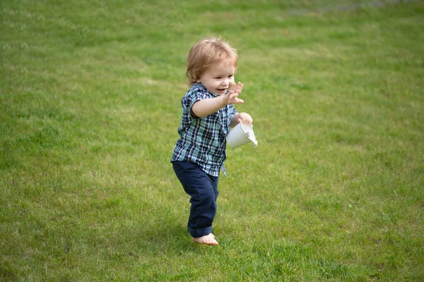 Baby staat blootsvoets op het groene gazon. — Stockfoto