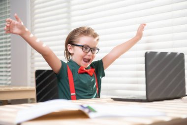 Öğrenci internette ders çalışıyor. Evde eğitim. Çocuklar uzaktan öğreniyor. Laptop kullanan sevimli bir çocuk. Eğitim, çevrimiçi öğrenim, ev ödevi, okul çocuğu kavramı.