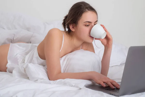 Genç bir kadın oturma odasında kahve ve dizüstü bilgisayarla iyi vakit geçiriyor.. — Stok fotoğraf
