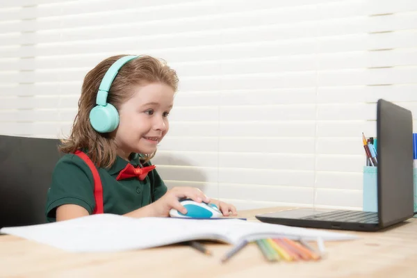 Chlapec ve sluchátkách používající doma notebook. Domácí výuka, dálkové vzdělávání, online elearning. — Stock fotografie