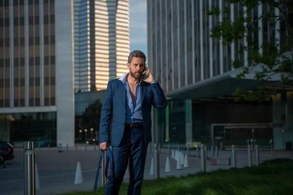 Homem de negócios moderno falando ao ar livre telefone com paisagem urbana no fundo. — Fotografia de Stock