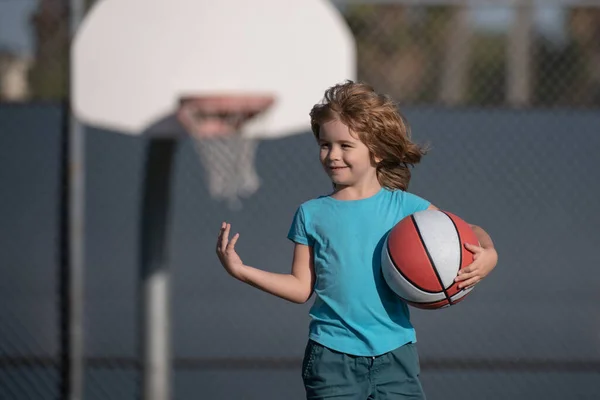 Gelukkige kleine jongen basketbal spelen op de speelplaats. — Stockfoto