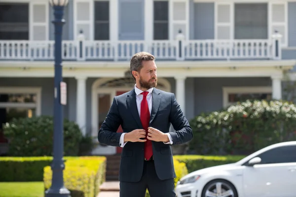 Affärsman som står utanför ett modernt hus. Fastighetskoncept. Agent redo att sälja hem. — Stockfoto