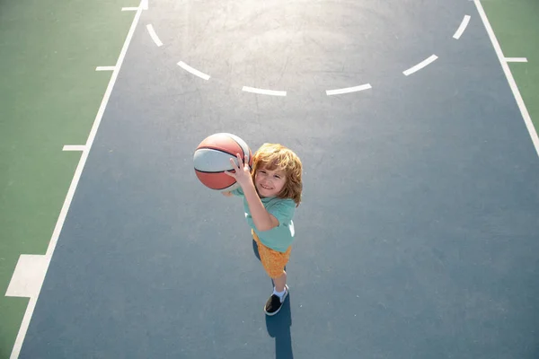 Miúdo a jogar basquetebol com bola. Vista de ângulo de cima do menino preparando-se para o tiro bola cesta. — Fotografia de Stock