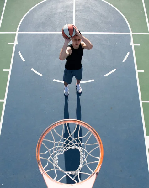 Koszykarz. Sport i koszykówka. Człowiek skacze i rzuca piłkę do kosza. — Zdjęcie stockowe
