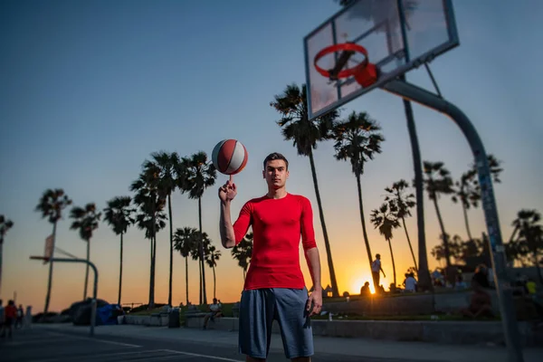 Halten Basketballball auf Venedigs Beach-Basketballfeld. Handspinnender Korbball. Basketball auf dem Finger balancieren. — Stockfoto