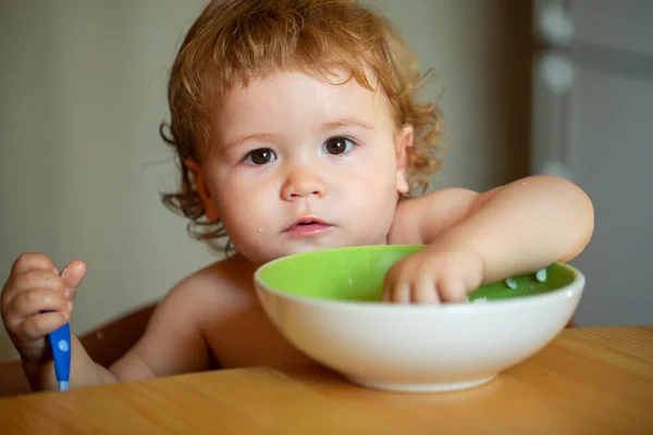 Retrato de engraçado menino comendo de prato segurando colher close-up. — Fotografia de Stock