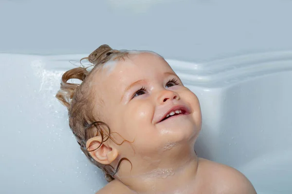 Veselá dětská tvářička v bublinkové koupeli. Vtipné, šťastné dítě se koupe ve vaně s vodou a pěnou. Dětská hygiena. — Stock fotografie