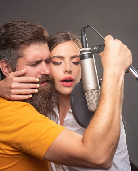 Zingende man en vrouw in een opnamestudio. Sensueel koppel met microfoon. Karaoke signer, muzikale zanger. — Stockfoto