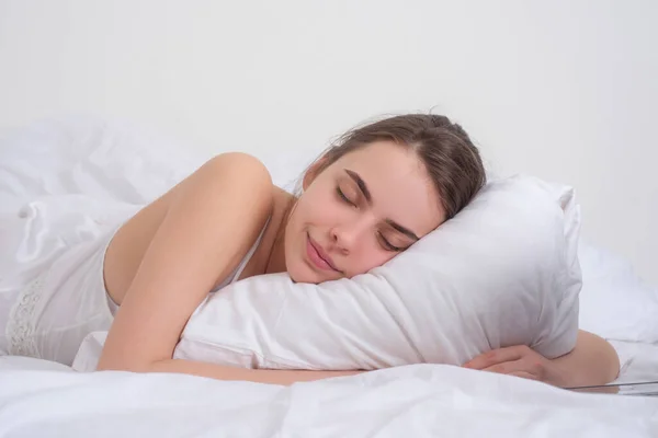 Wanita muda tidur nyenyak di tempat tidur memeluk bantal putih lembut. Gadis istirahat, tidur yang nyenyak. Wanita tidur. Wanita muda yang cantik berbaring di tempat tidur dan menutup mata sambil ditutupi selimut. — Stok Foto
