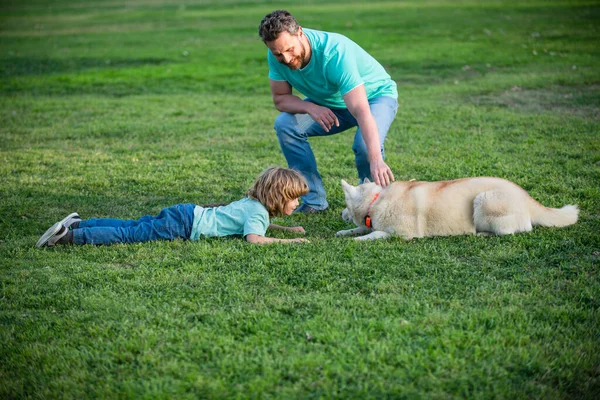 父と息子は公園で犬と遊ぶ。父と子供は屋外で楽しんでいます. — ストック写真