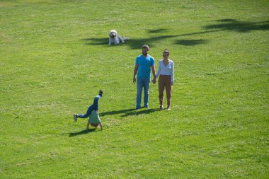 Mutlu aile yeşil çimlerin üzerinde birlikte dinleniyor, dışarıda eğleniyor..