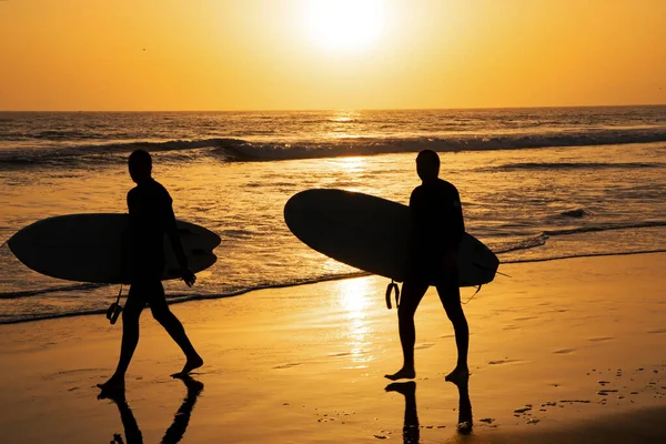 夏の旅行休暇のための日没や日の出と熱帯ビーチの海の海。サンセットビーチでサーフボードを担いでいるサーファーのシルエット。海の風景. — ストック写真
