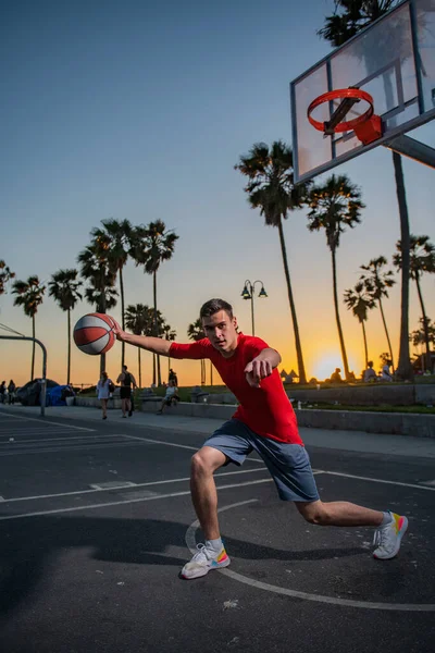 Спортивные мужчины играют в баскетбол на открытом воздухе в солнечный рассвет. — стоковое фото
