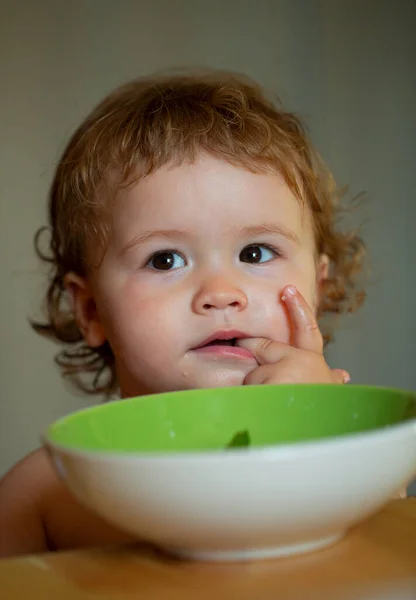Happy baby eating himself with a spoon. Lick tasty fingers. — Stock Photo, Image