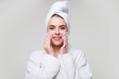 Genç bir kadın pamuk pedi kullanarak yüz derisini önemser..