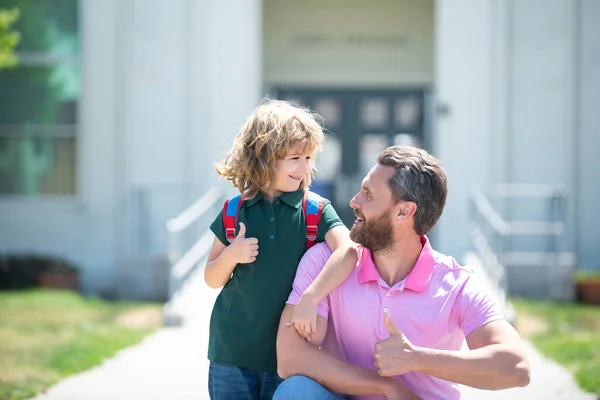 Un écolier qui va à l'école avec son père. Joyeux visage. Pouce en l'air signe. — Photo