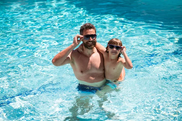 Vader en zoon zwemmen in het zwembad. Familie bij Aquapark. Papa en zoon in het zwembad. Zomers weekend. Familievakantie en zomervakantie. Zwembadfeest. — Stockfoto