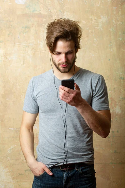 Muž se smartphonem, poslouchající hudbu. Gay chlap s telefonem a sluchátky. — Stock fotografie