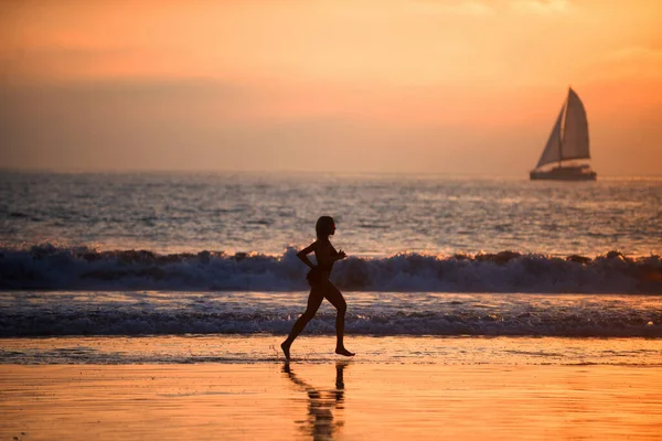 サンセット時にビーチで走るランナー女. — ストック写真