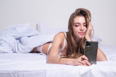 Yatakta bir kadın akıllı telefonuyla sosyal uygulamaları kontrol ediyor. Seksi kız video çekiyor, sabahları yatakta yatıyor..