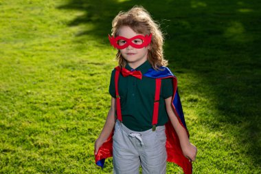 Süper kahraman çocuk dışarıda eğleniyor. Doğaya karşı süper kahraman çocuk. Süper kahraman kostümü giyen ve dışarıda eğlenen bir çocuk..