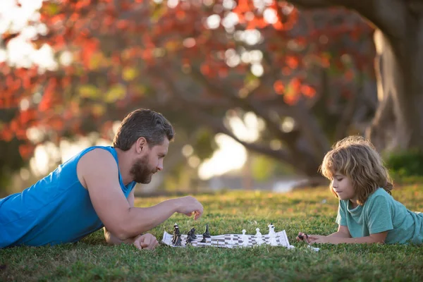 父と息子の子供は一緒に屋外で時間を費やしてチェスをする. — ストック写真