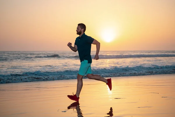 Sportlicher Männerlauf im Sommer. Mann läuft bei Sonnenuntergang am Strand. Fit-Man-Fitnessmodell arbeitet im Freien am Strand. — Stockfoto