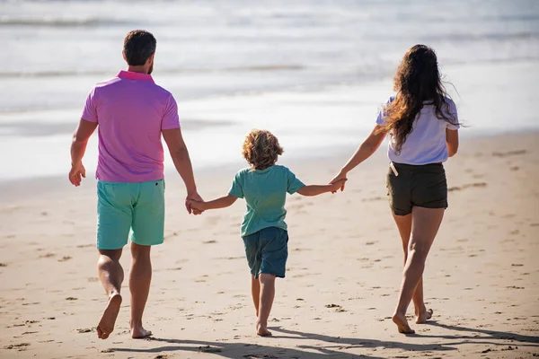 Famiglia felice sulla spiaggia. Persone che si divertono durante le vacanze estive. Padre, madre e figlio sul mare blu. Concetto di famiglia spensierata. I genitori con bambino si rilassano all'aperto. Weekend concetto di famiglia. — Foto Stock