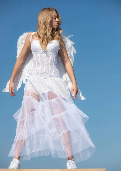 Chica ángel de San Valentín con alas blancas. Mujer con alas de ángel con arco y flecha contra el cielo azul. Adolescente ángel. — Foto de Stock