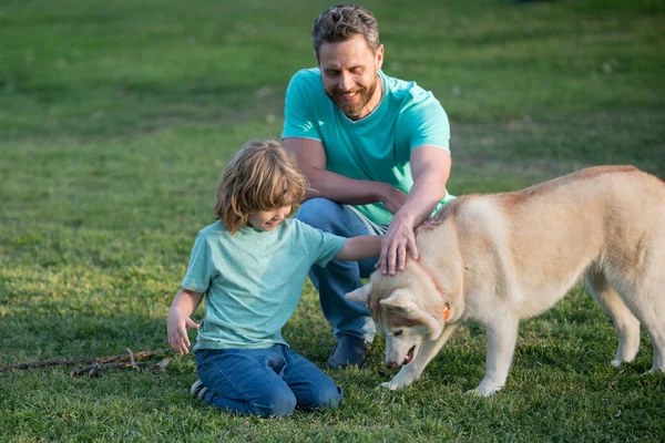 Padre e hijo con perro mascota relajándose en la naturaleza en el parque de primavera. —  Fotos de Stock