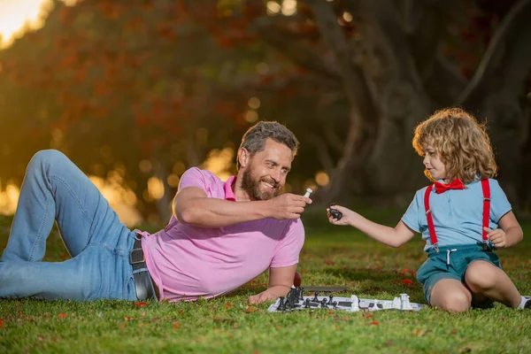 Otec a syn hrají šachy a tráví spolu čas venku. Muži mají rádi šachy. Portrét mužské generace. — Stock fotografie