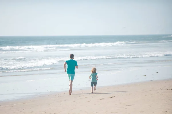 父と息子は海を走っている。父と子供は屋外で楽しんでいます。家族旅行、休暇、父の日の概念. — ストック写真