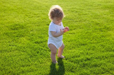 Küçük bebek çimlerin üzerinde emeklemeyi öğreniyor. Çocuk aylarını düşün. Yeşil çimlerde oynayan mutlu çocuk.