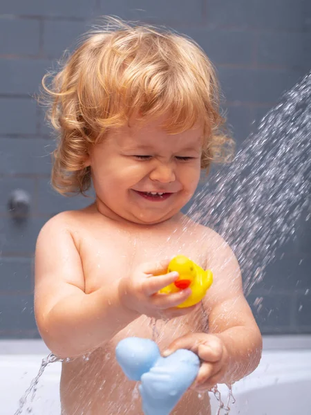 Douche d'enfant. Bébé heureux prenant un bain jouant avec des bulles de mousse. Petit enfant dans une baignoire. Enfant souriant dans la salle de bain avec canard jouet. Lavage et bain des nourrissons. Soins et hygiène des enfants. — Photo