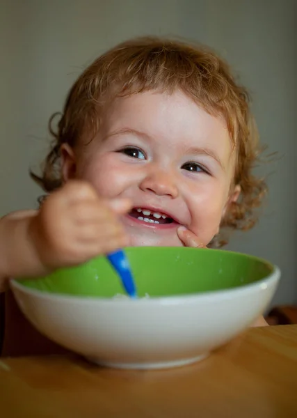 Baby houdt een lepel in zijn mond. Gelukkig kind eet zichzelf op met een lepel. Lancering van het eten van voedsel door kinderen. — Stockfoto
